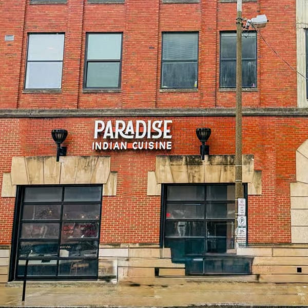 Exterior of Paradise Indian Cuisine, a red brick building with large windows and a street lamp.