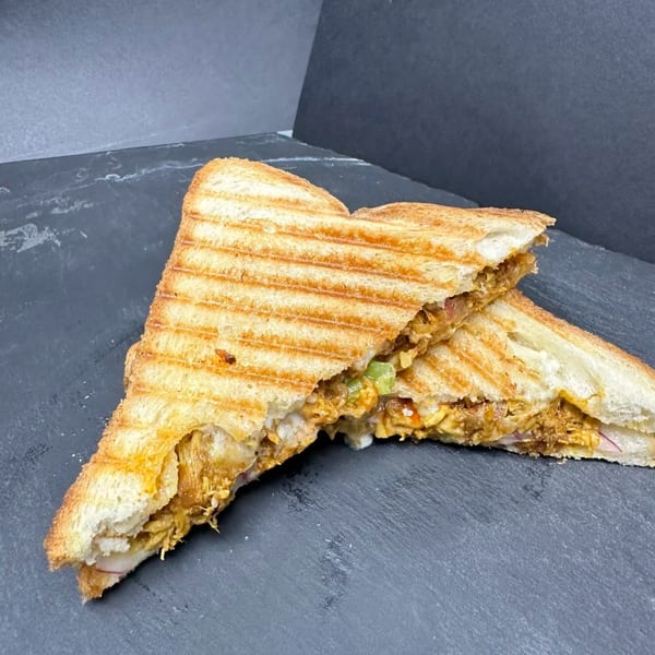 A grilled sandwich, cut in half diagonally, revealing a savory filling of chicken and melted cheese.