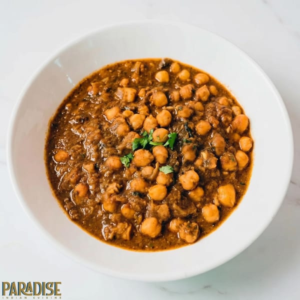 A white bowl filled with chana masala, a chickpea curry, garnished with fresh cilantro.